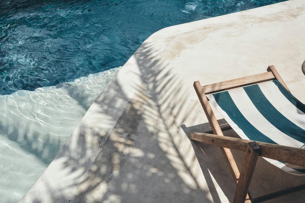 pexels-photo-2736543-2736543 Serene poolside lounger with palm shadows, perfect for summer relaxation in Bali.